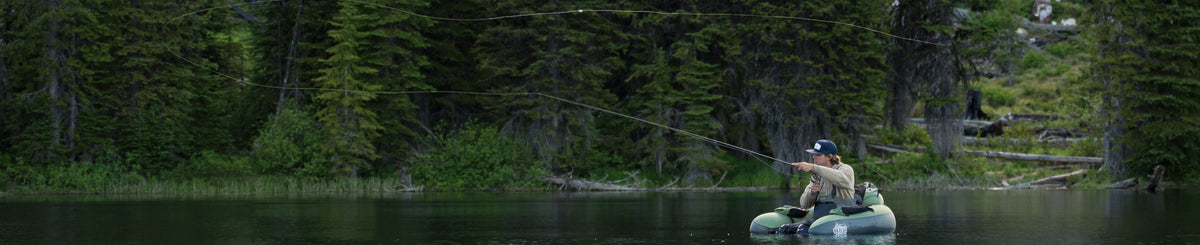 Person fishing on a small boat in a lake surrounded by trees
